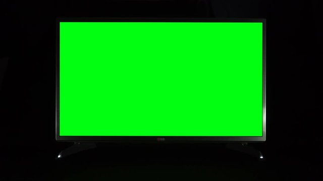 Modern TV with green screen on black background
