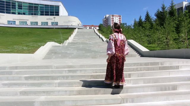 Girl in a national Sarafan climbs the stairs and dances