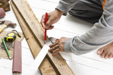 Male carpenter working with wood pencil with machinist square at work place.Background craftsman tool.Zoom in