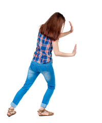 back view of woman pushes wall.  Isolated over white background. Rear view people collection. backside view of person. Girl in plaid shirt shoves something in the side.
