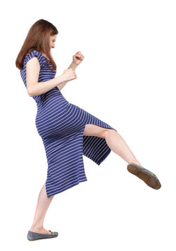 skinny woman funny fights waving his arms and legs. Isolated over white background. The brunette in a blue striped dress has a foot.