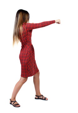 skinny woman funny fights waving his arms and legs. Isolated over white background. The girl in red plaid dress stands sideways and punches.