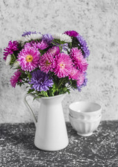 Autumn flowers asters in a white pitcher on a light background. Still life in vintage style