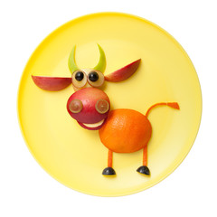 Funny bull made of orange and apple on yellow plate