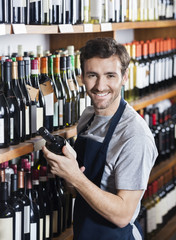 Confident Salesman Arranging Wine Bottle On Shelf