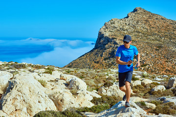 Fototapeta premium man runs on a cliff against a blue sea