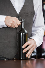 Midsection Of Bartender Opening Wine Bottle