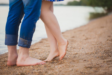 Fototapeta na wymiar Loving couple sitting on the beach, feet close-up