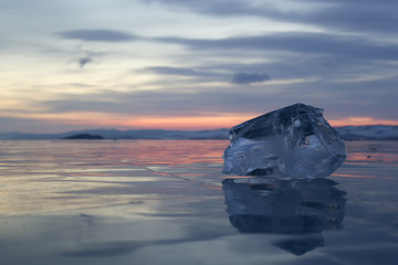 A piece of ice lying on the frozen surface of lake Baikal at daw