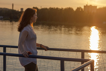 Stylish young woman enjoying the landscape at sunset .