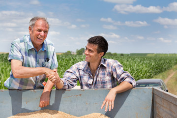 Farmers shakig hands on pile of grains