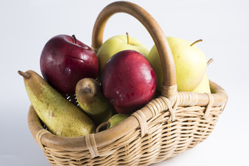 wicker basket full of fruits like pears and apples of different quality.