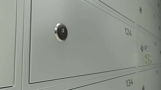 Line of safe deposit boxes in a bank and inserted key with dollar sign keychain. Shallow focus 4K dolly shot