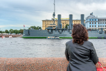 Young girl admires the cruiser Aurora, the Neva River and the historic center of St. Petersburg