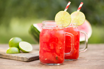 Watermelon smoothies with lime and watermelon sliced ripe on wooden table. Green background.