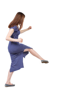 skinny woman funny fights waving his arms and legs. Isolated over white background. The brunette in a blue striped dress beat someone down.