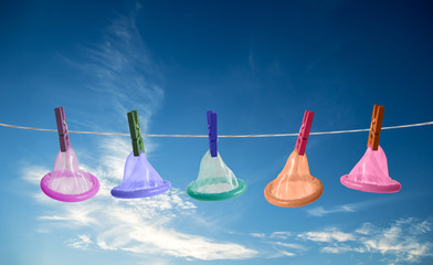 Condoms hanging on rope on sky background.