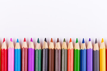 Colored pencils in a row on a white background. Top view with copyspace