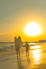Silhouette of happy family watching the sunset, walking beach outside background