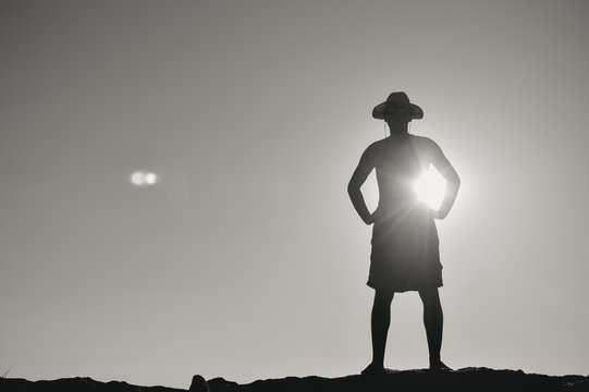 Back view silhouette of man standing backlight sunset summer evening, lens flare sky outdoors background