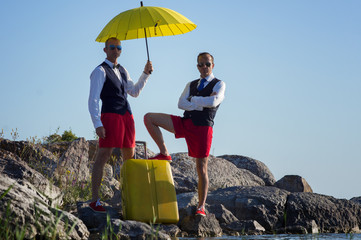 Two businessmen with a suitcase, traveling on the rocks