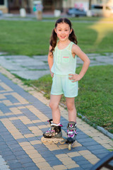 Little pretty girl on roller skates at a park