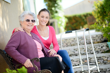 cheerful old woman in wheelchair with her young granddaughter outdoor in hospital