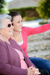 Fototapeta premium cheerful old woman in wheelchair with her young granddaughter outdoor in hospital