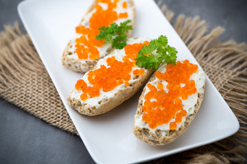 Red caviar on bread on white plate.