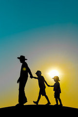 Beautiful sunset silhouette of father with kids, outdoors background