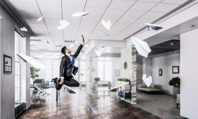 Jumping businessman in office . Mixed media