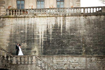 A look from afar on a bride kissing a groom standing on the ston