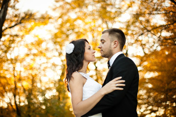 Fototapeta premium Groom looks at a bide seriously standing in the autumn park