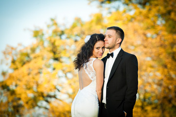 Curly brunette bride in a gown with open back leans to a groom