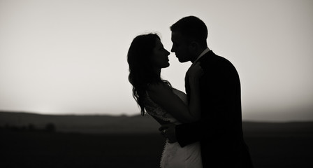 Black and white picture of newlyweds hugging on an empty field