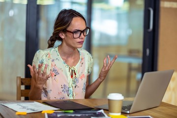 Frustrated female graphic designer looking at laptop