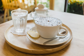 cup hot coffee and Syrup in bottle glass on table