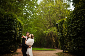 Bride wih plaits kisses a groom in cheek while posing between hu