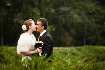 Groom smiles kissing a bride with flowers in her hair