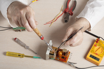 Hand of electrician with multimeter probe at  electrical switchgear cabinet. Engineering tools