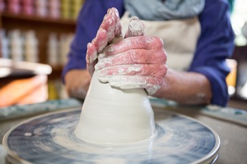 Mid section of female potter making pot