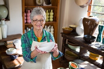 Happy female potter holding bowl
