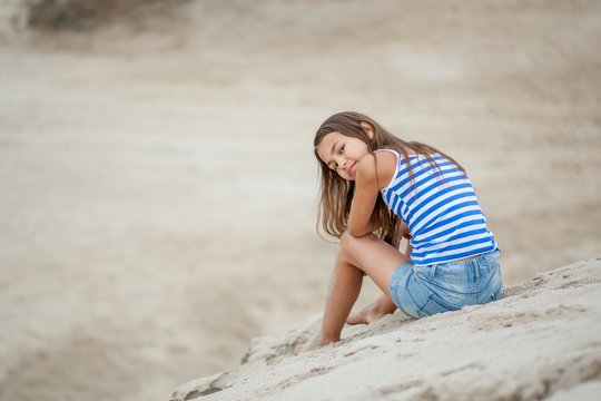 girl in a striped vest on the sand