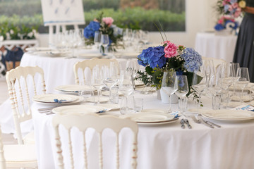 Original white chairs stand around rich dinner table