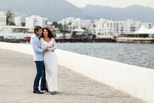 Man In Light Blue Jacket Hugs A Woman In Long White Gown