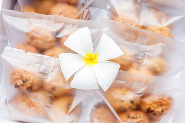 Oatmeal cookies in plastic bag package with flower decoration.