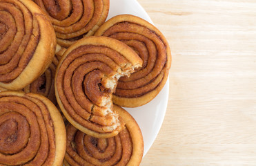 Plate of pecan sweet rolls on a wood table with one bitten.