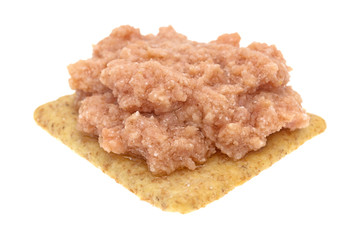 Deviled ham a whole wheat cracker on a white background.