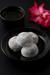 Japanese sweet black sesame daifuku on black wooden background