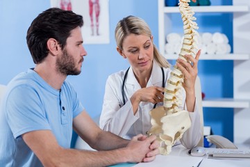 Physiotherapist explaining the spine model to patient